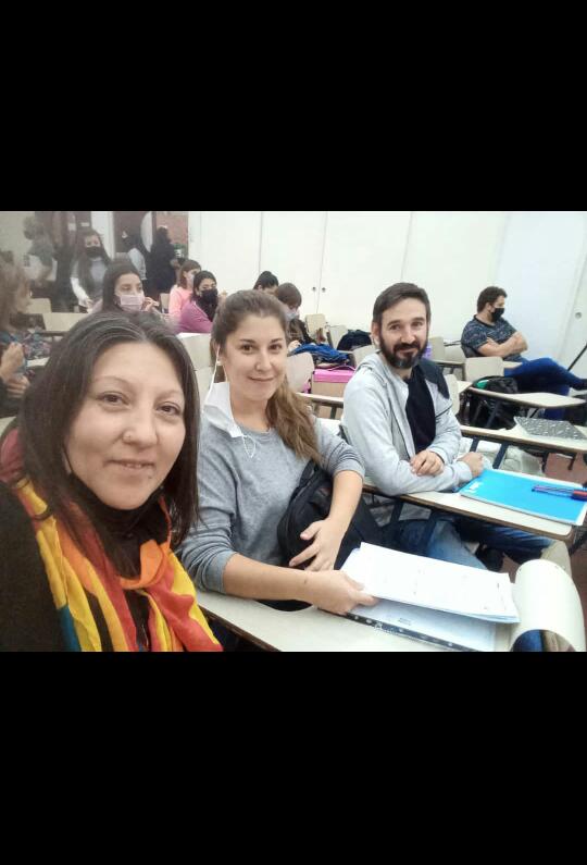 Tres estudiantes junto a sus compañeros y compañeras dentro del aula